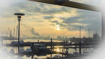 Een haven met boten, een kraan en windturbines op de achtergrond.