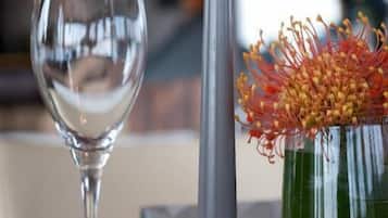 Una candela su un tavolo, un bicchiere e un vaso con fiori.