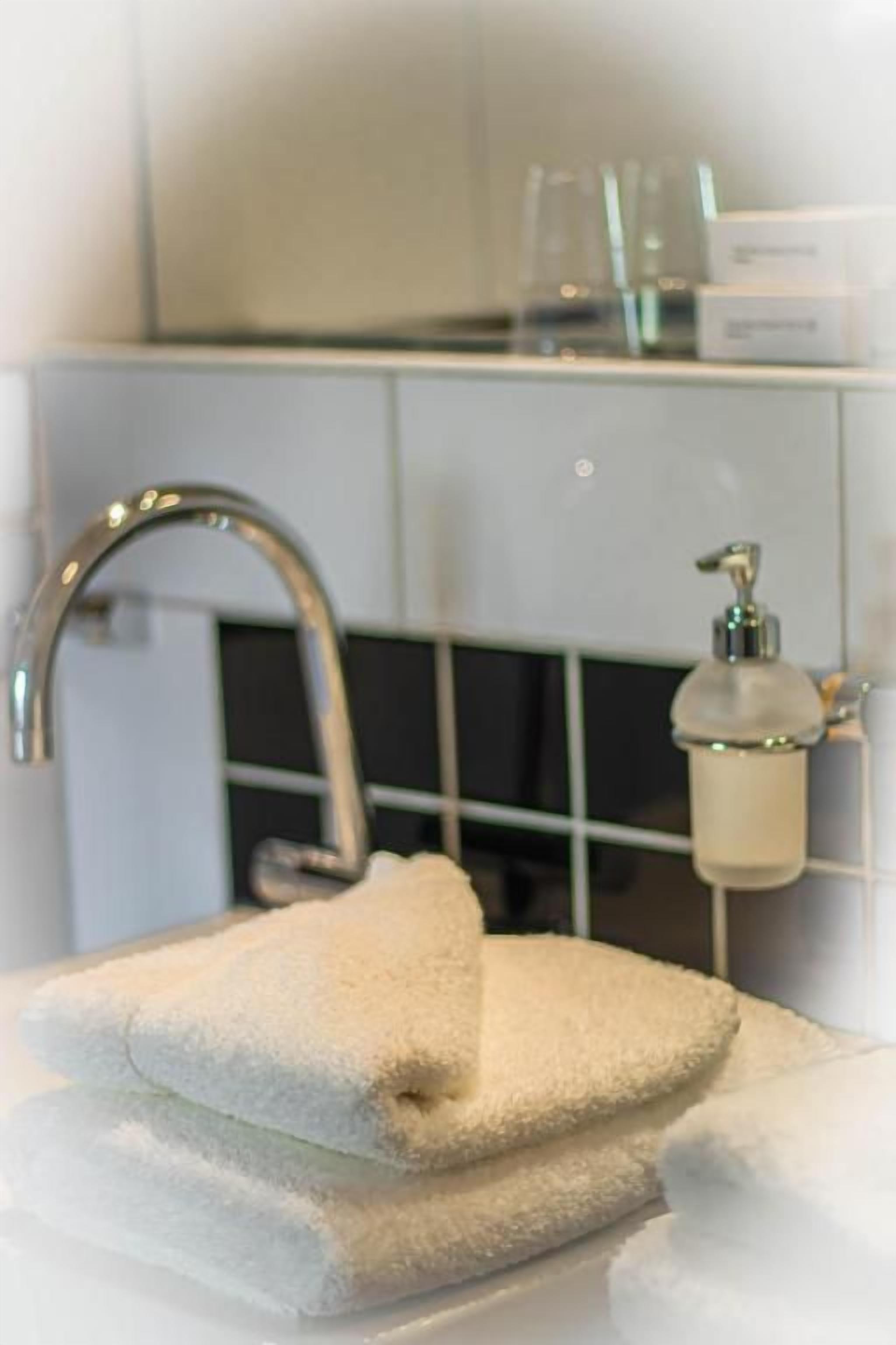 A bathroom with a sink, a towel, and a soap dispenser.