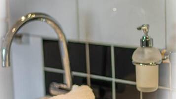 A bathroom with a sink, a towel, and a soap dispenser.
