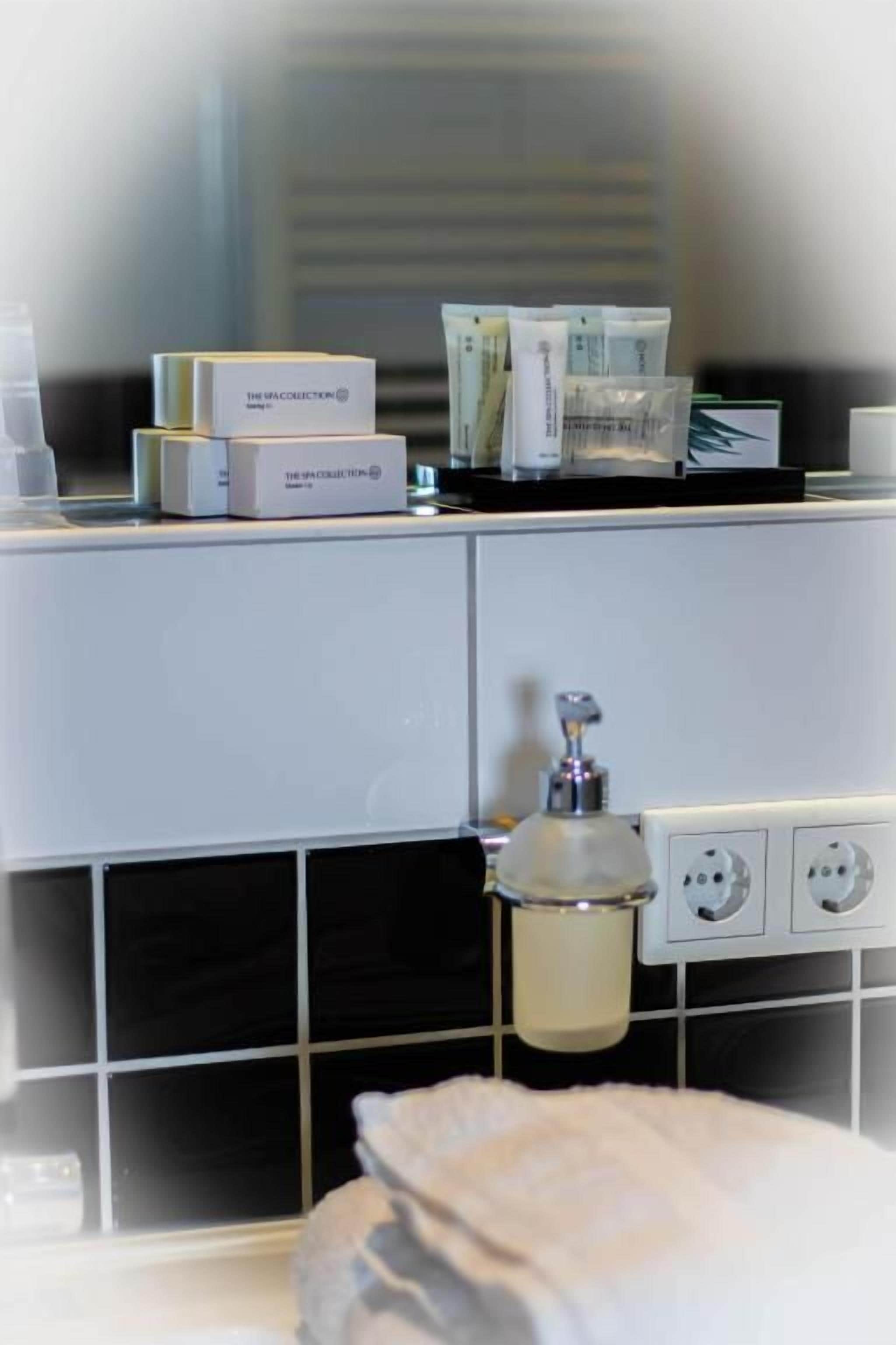 A bathroom with a white sink, a mirror, and toiletries on the counter.