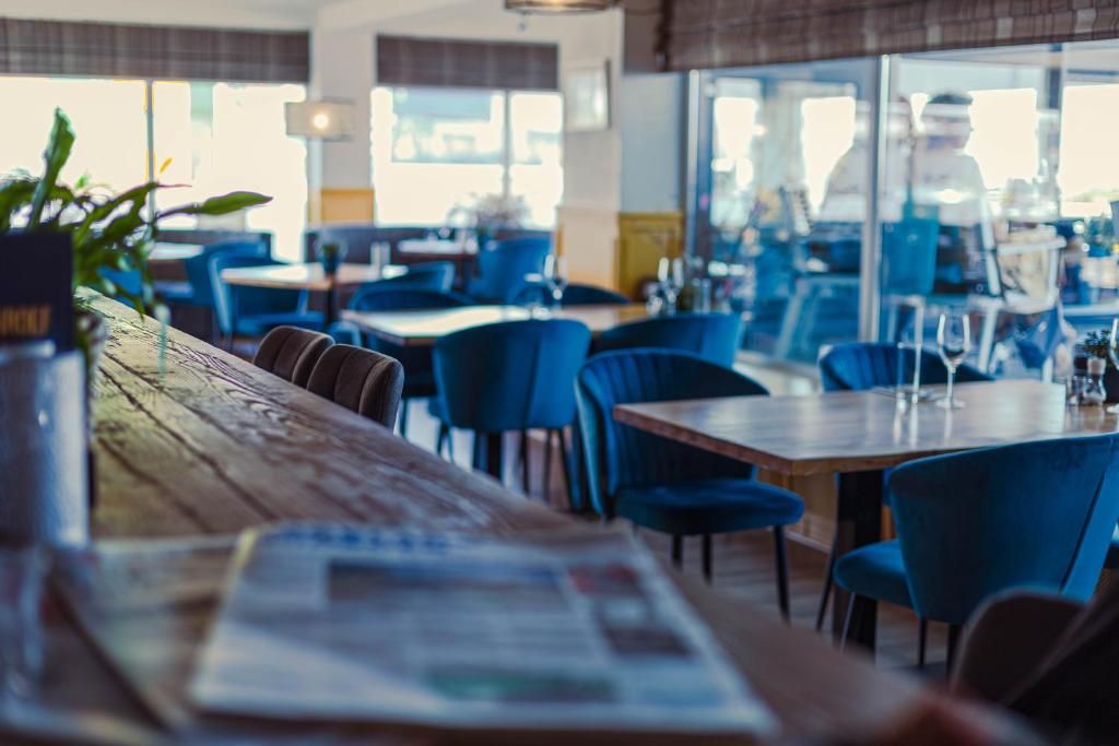 Interior de restaurante con mesas, sillas, una barra de madera y vistas a través del ventanal.