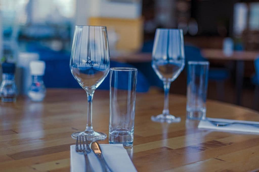 A dining table with empty wine glasses and cutlery, suggesting a restaurant setting.