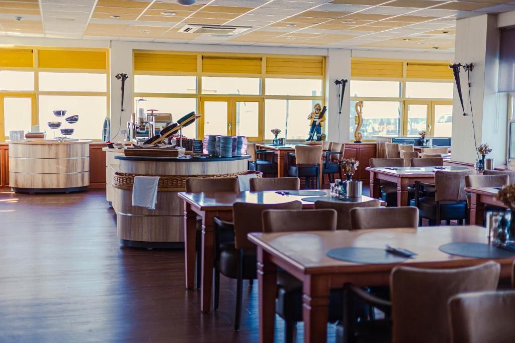 Um restaurante espaçoso com pé direito alto, grandes janelas e diversos arranjos de assentos, incluindo mesas e cadeiras.