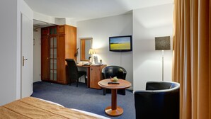 Une chambre d’hôtel comprenant un lit, un bureau avec une lampe, une chaise, une télévision et une armoire.
