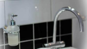 Een badkamer met een wit wastafel, een handdoek, een spiegel en een zeepdispenser.