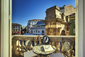 Un balcón con vistas a edificios históricos, una mesa de baldosas y un sombrero.
