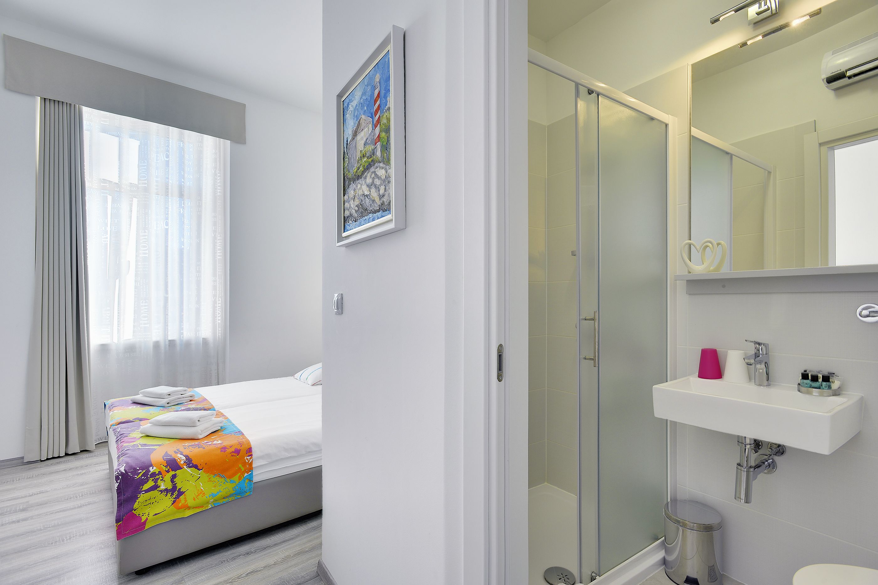 Una habitación de hotel moderna con una cama, ducha y baño con lavabo y espejo.