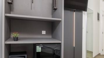 Una habitación moderna con estanterías grises, un televisor de pantalla plana y una planta pequeña.