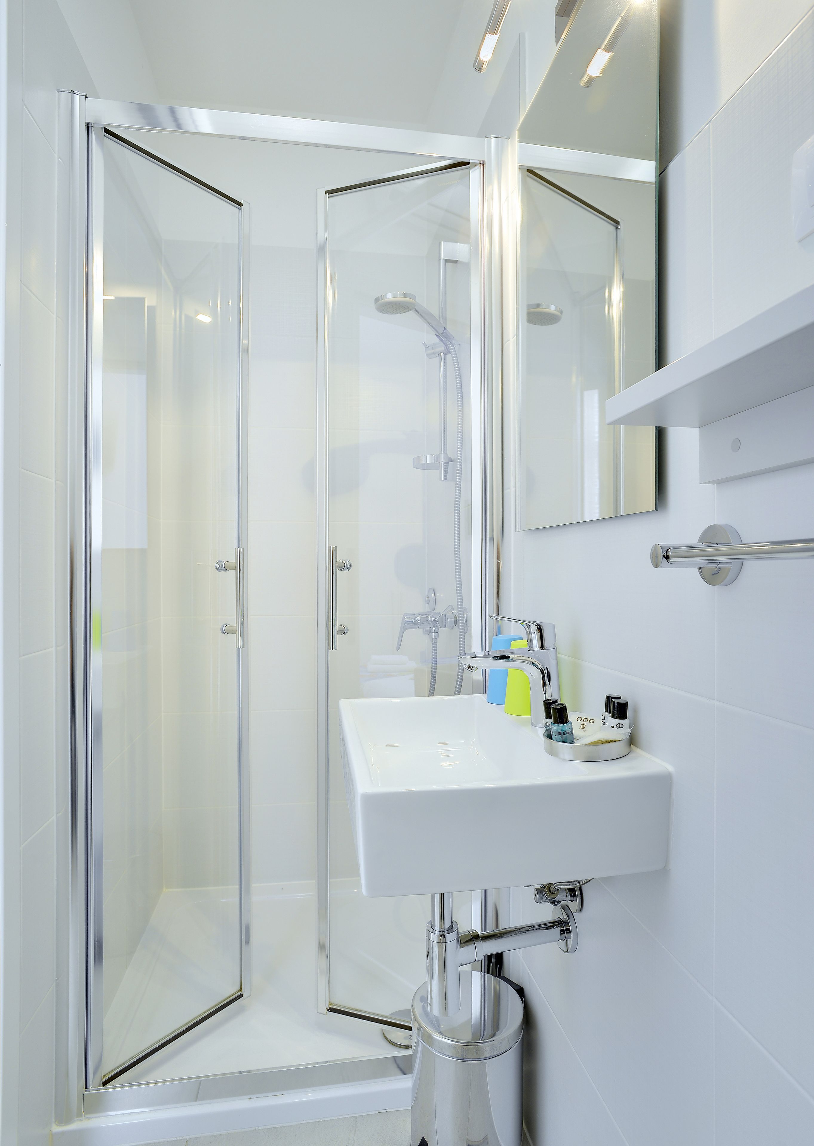 Un baño moderno con cabina de ducha de vidrio, un lavamanos blanco y un espejo sobre él.