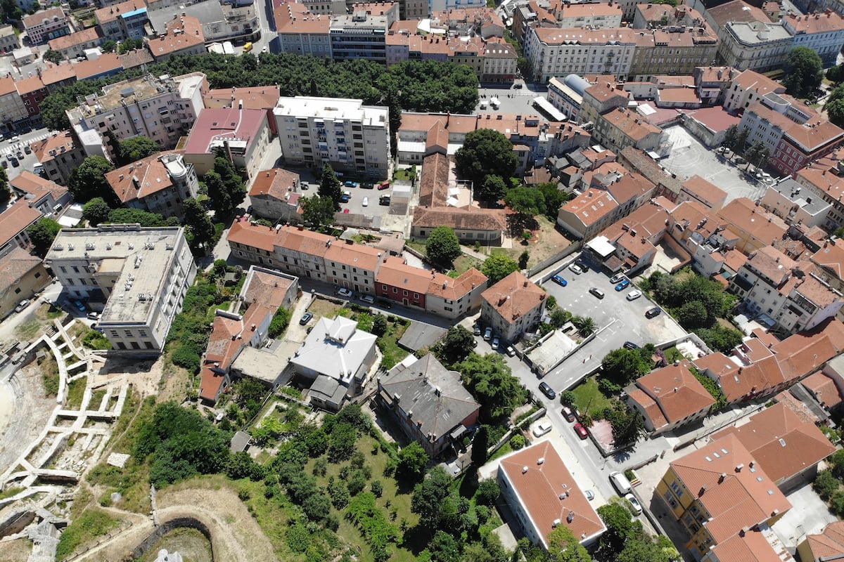 An aerial view of a densely packed urban area with various buildings, including multi-story residential and commercial structures.