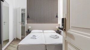 Ein Hotelzimmer mit Bett, Nachttischen, einem Spiegel, einer Hängelampe und einer Schiebetür.