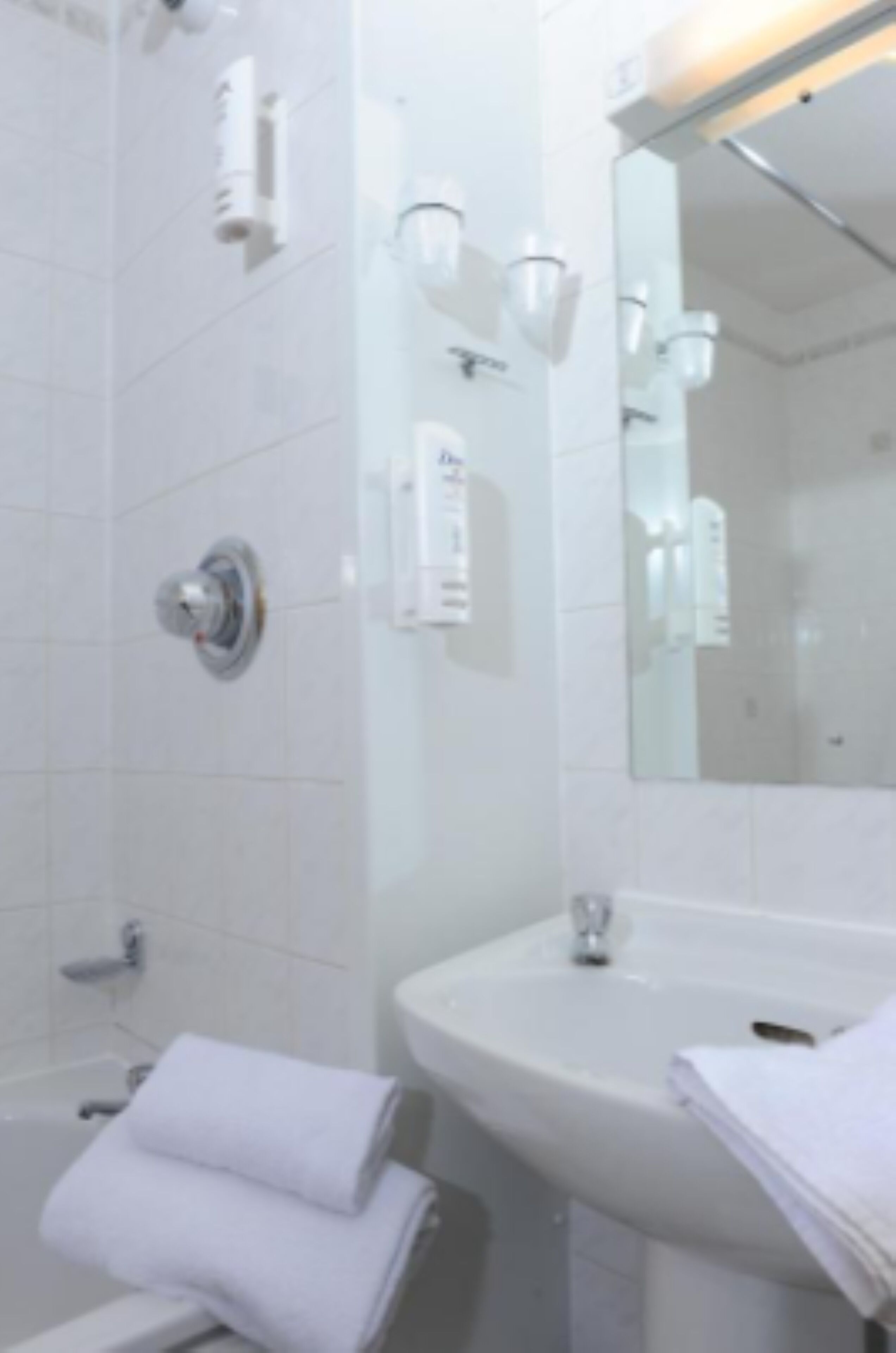A bathroom with a white sink, mirror, and towel rack.