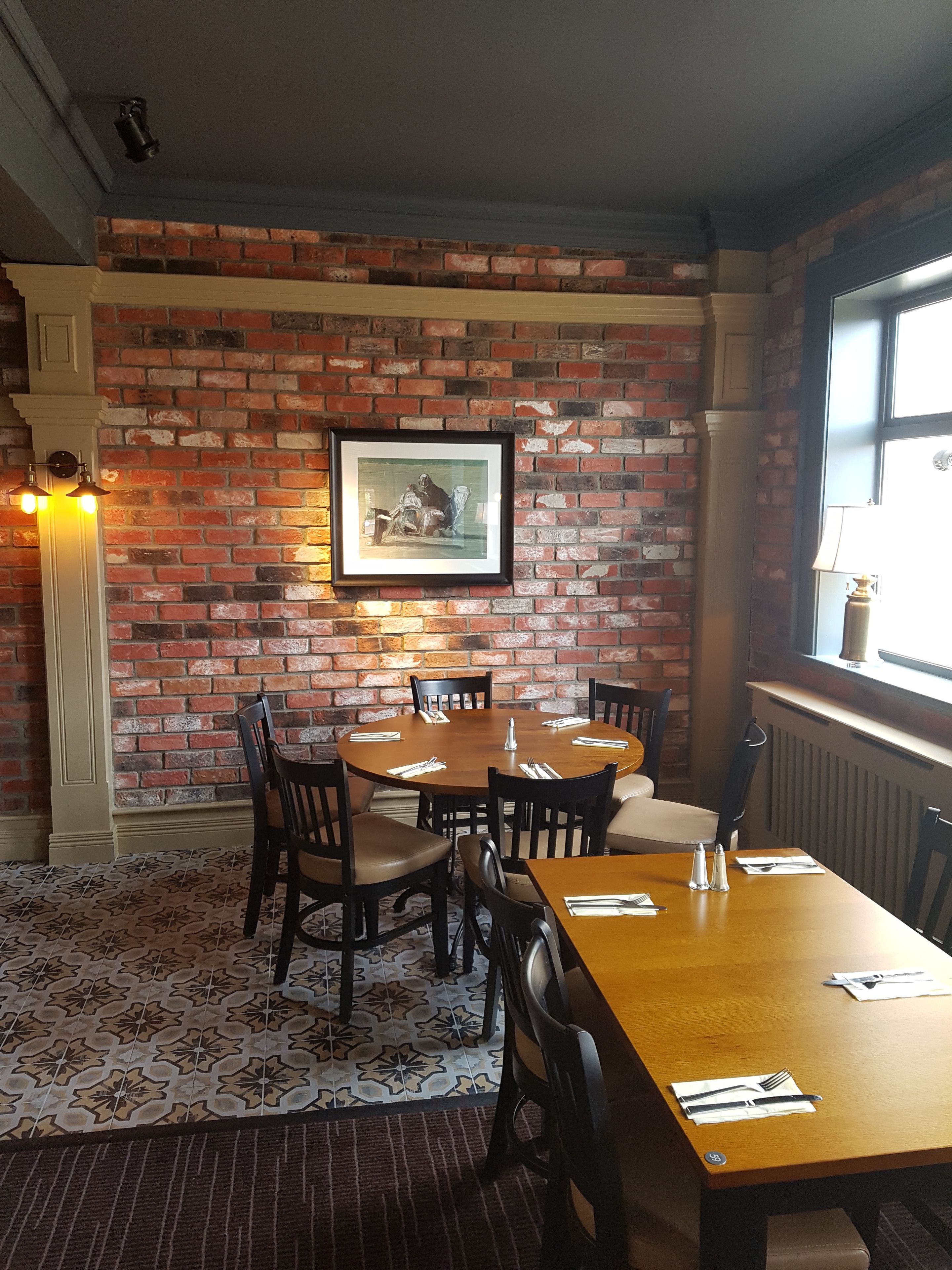 A dining area with a brick wall, a framed picture, and a window with a view.