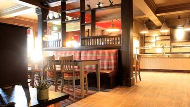 Un restaurant acollidor amb una cadira de fusta, seients i una zona de bar.