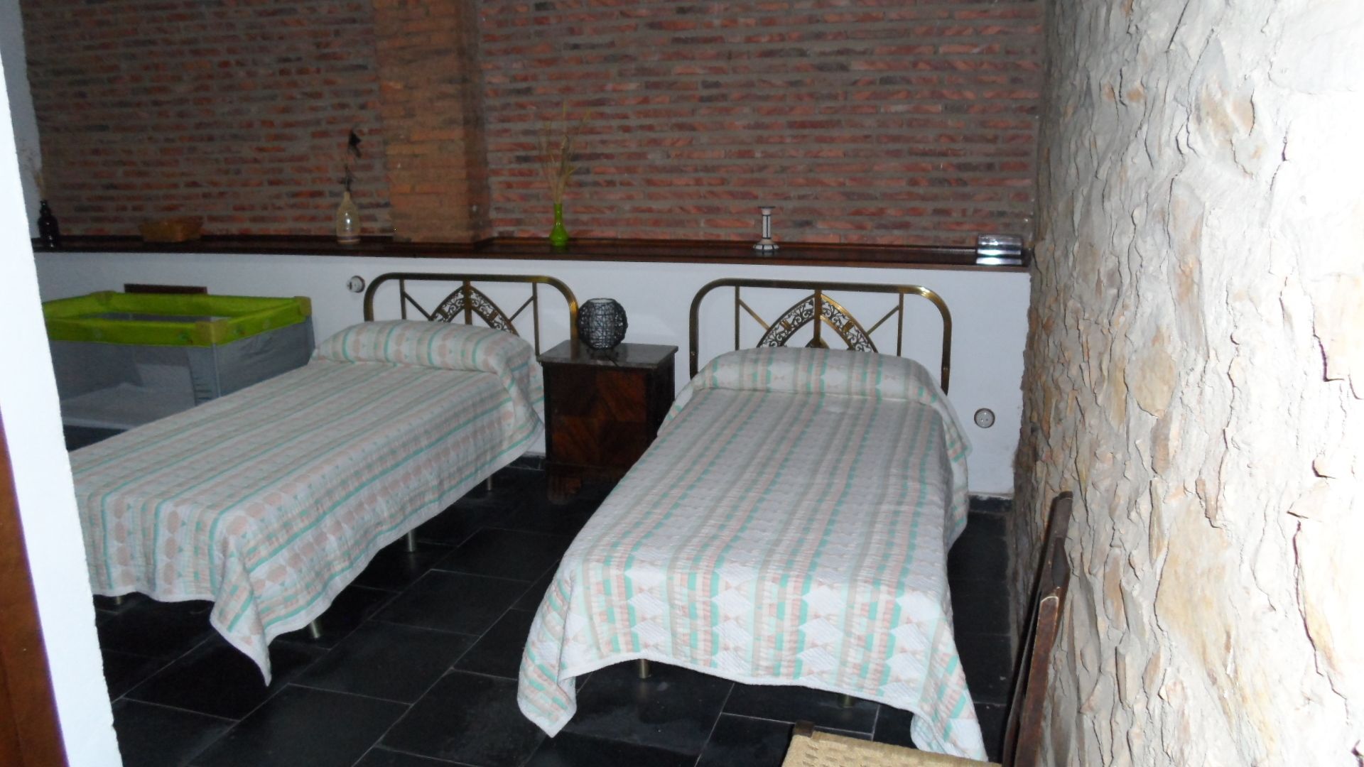 A small room with two single beds, a brick wall, and a wooden floor.