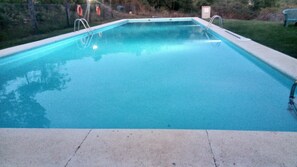 Une piscine rectangulaire à l’eau d’un bleu limpide, entourée d’une terrasse en béton.