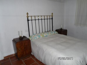 Une chambre à coucher comprenant un lit, une table de chevet, une commode et une lampe fixée au mur.