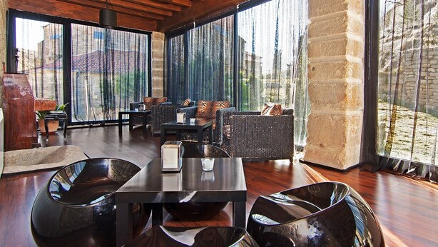 Una habitación amplia con techo de madera, ventanas grandes y pared de piedra.
