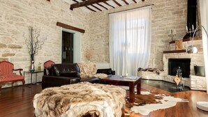 Una sala rústica con paredes de piedra, chimenea, muebles de cuero y un manto de piel.