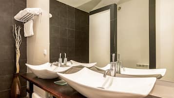 A bathroom with two white vessel sinks, a wooden vanity, a towel rack, and a mirror.