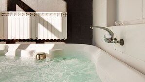 Una bañera con grifo, un taburete y una ventana con persianas.