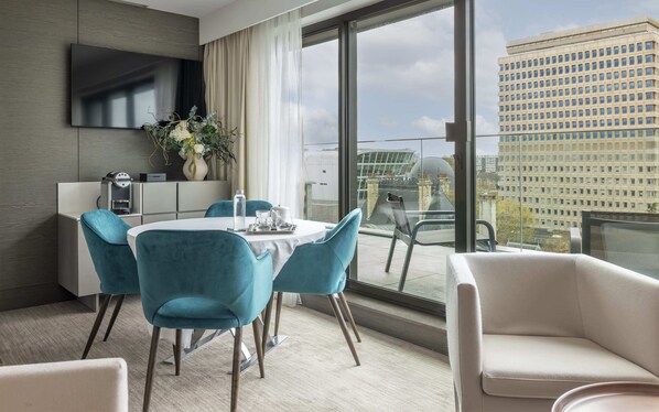 A modern hotel room with a large window, a flat-screen TV, a dining table with chairs, a sofa, and a coffee machine. - Le Saint-Antoine Hotel & Spa, BW Premier Collection (Rennes)