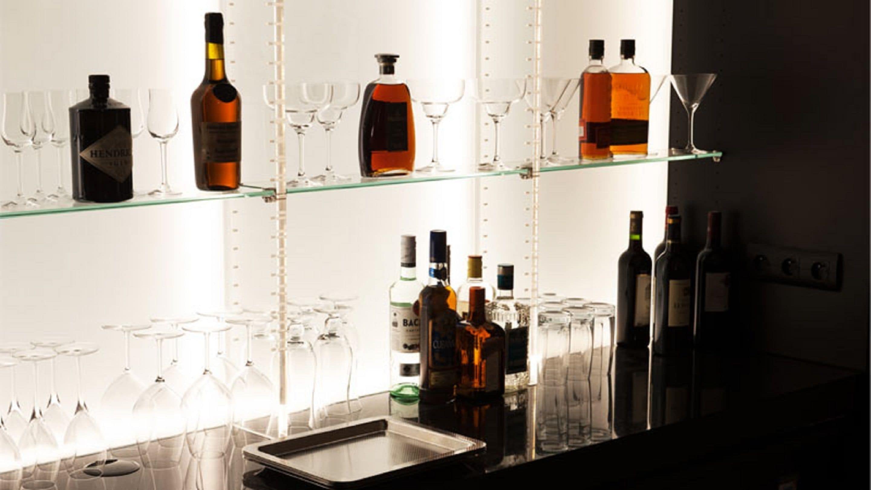 A bar area with shelves holding various bottles and glasses.