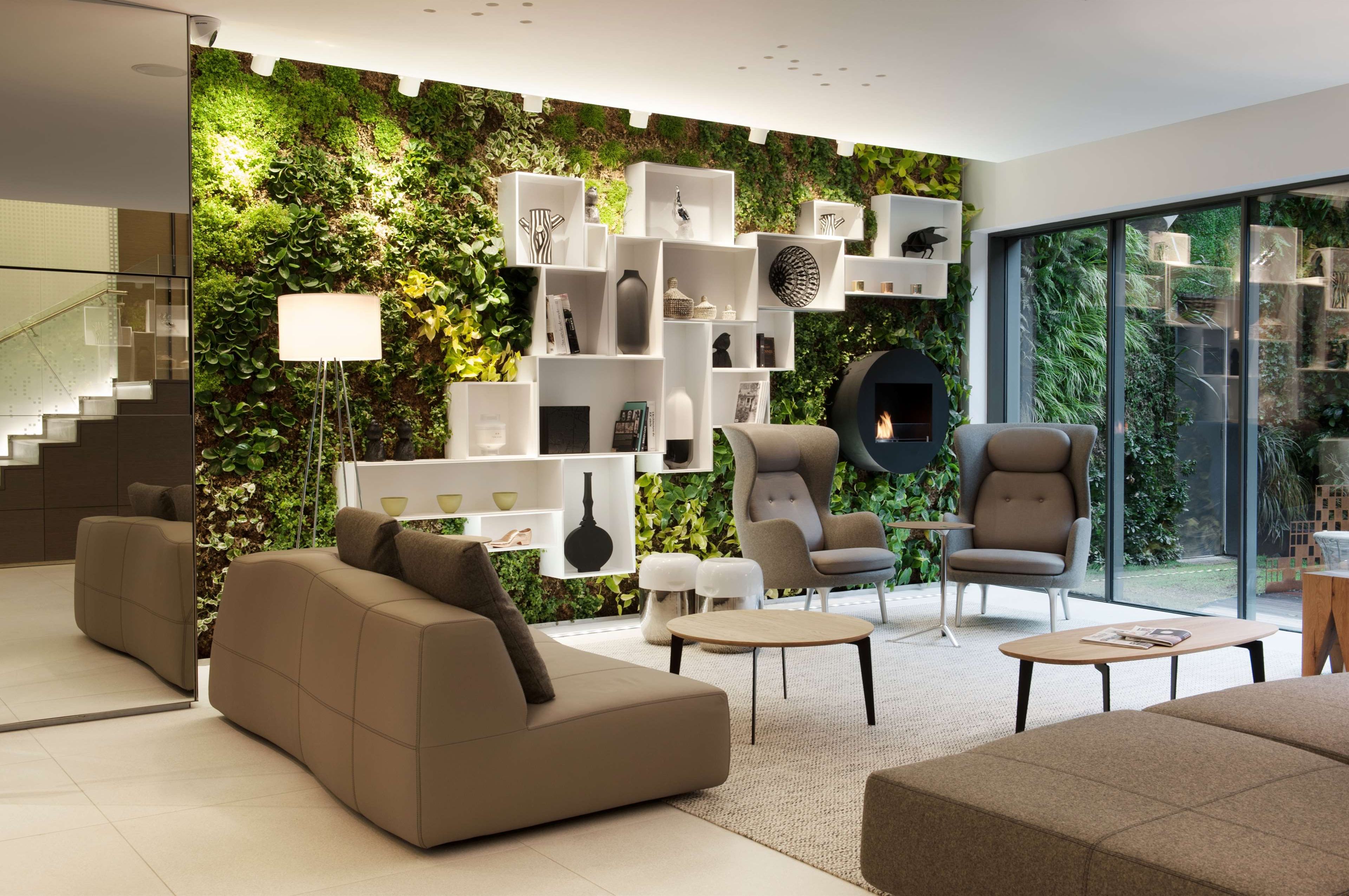 Un salon moderne avec un mur vert, des étagères blanches et des sièges confortables.