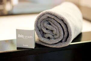 Une serviette enroulée avec une étiquette indiquant « savon des hôtels ibis Styles » sur une surface noire.
