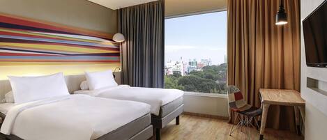 A hotel room with two beds, a desk, a chair, a TV, and a large window with a city view.