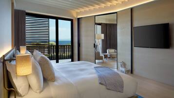 A modern hotel room with a large bed, a flat-screen TV, a balcony with a view, and a small seating area.