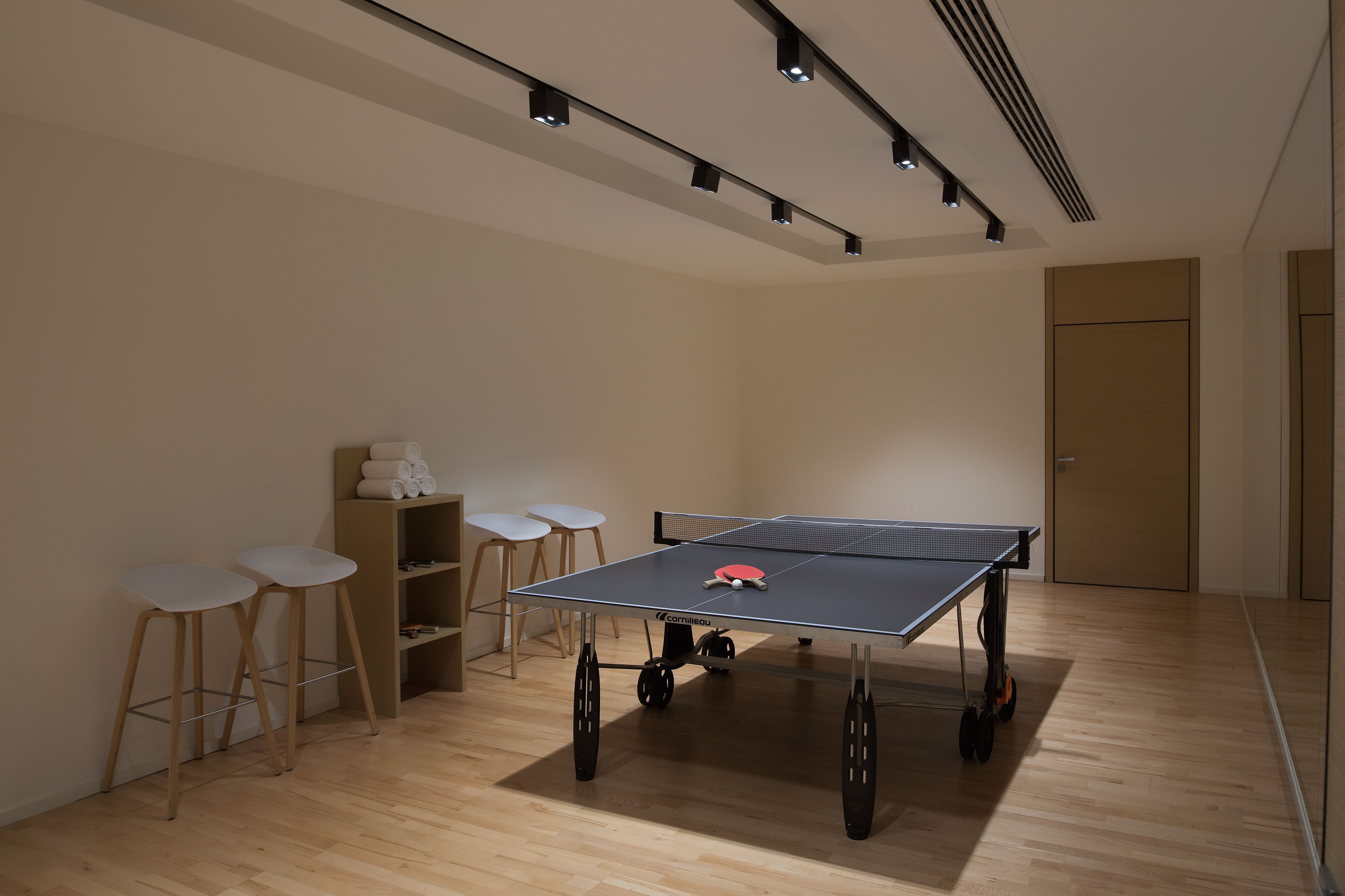 Ein Tischtennis-Tisch in einem Raum mit Holzboden, weißer Wand und einer Tür.