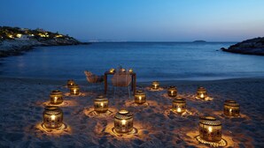 A beach setting with a table and chairs set up for dining, surrounded by evenly spaced decorative lanterns. - Six Senses Kaplankaya (Milas)