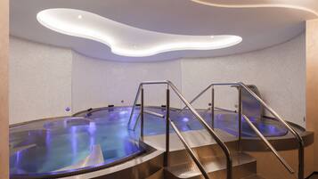 Un moderno espacio de spa con dos jacuzzis y escaleras metálicas que dan acceso a ellos.