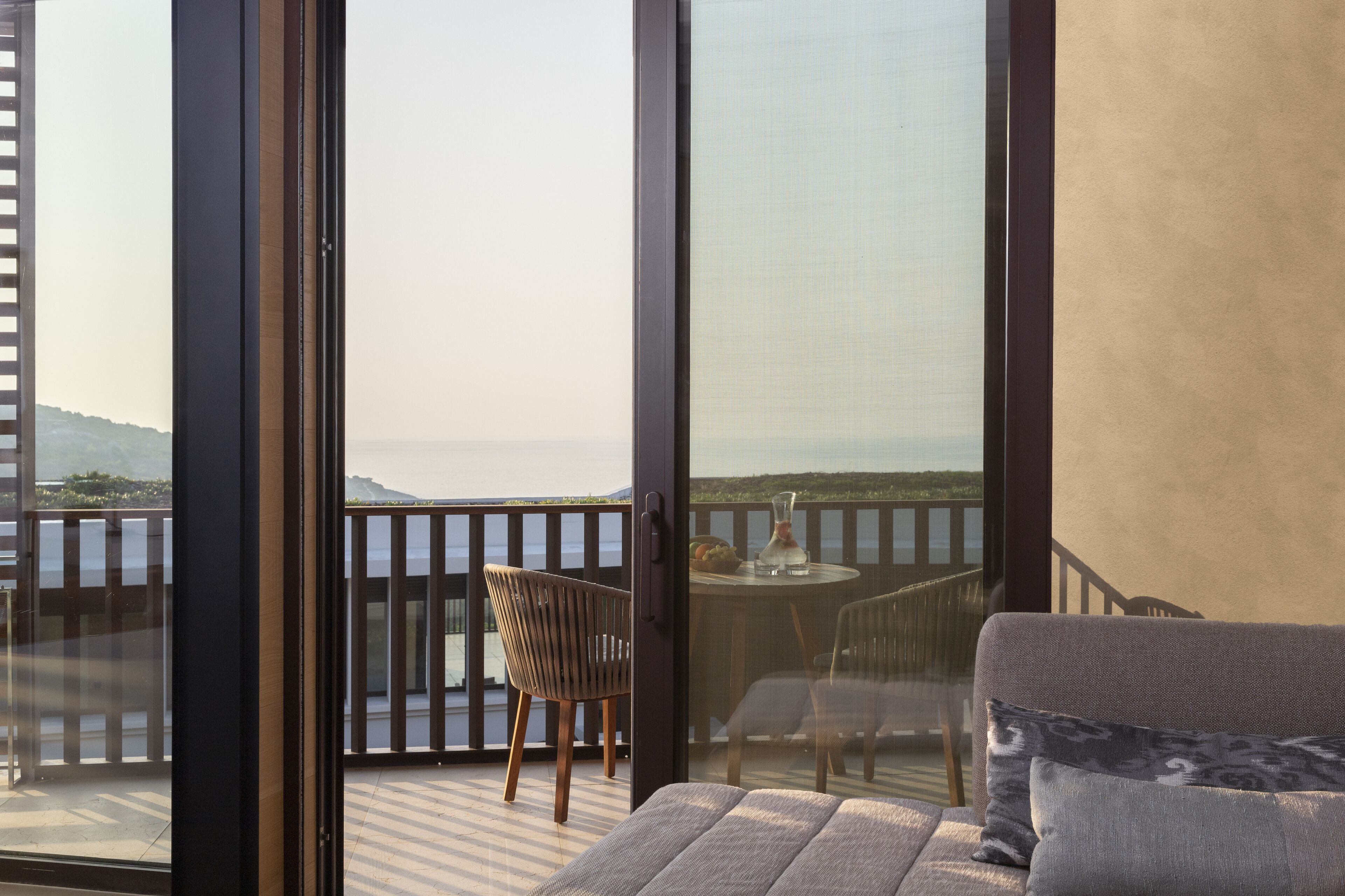 Un balcón con vista al mar, una mesa con sillas y un sofá.