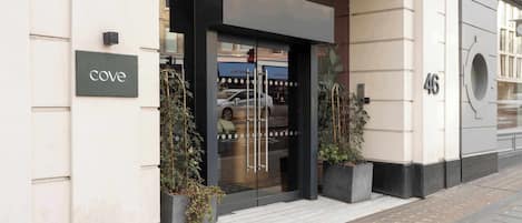 A building entrance with a glass door, a sign reading 'cove,' and a number '46' on the wall.