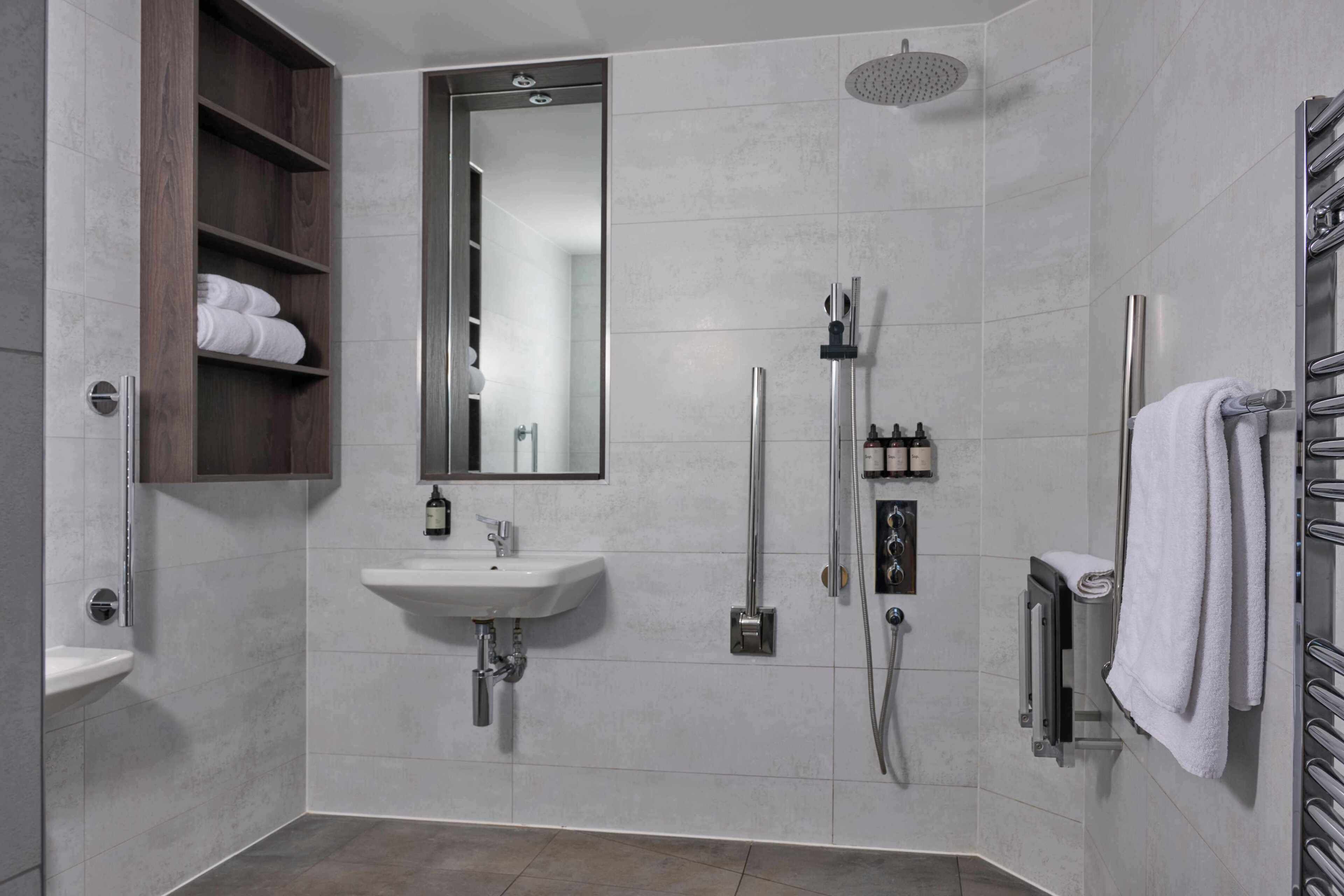 A modern bathroom with a built-in sink, a shower with a handheld showerhead, and a towel rack.