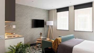 Una habitación de hotel moderna con una cama, un sofá, una pequeña mesa, un televisor y una ventana.