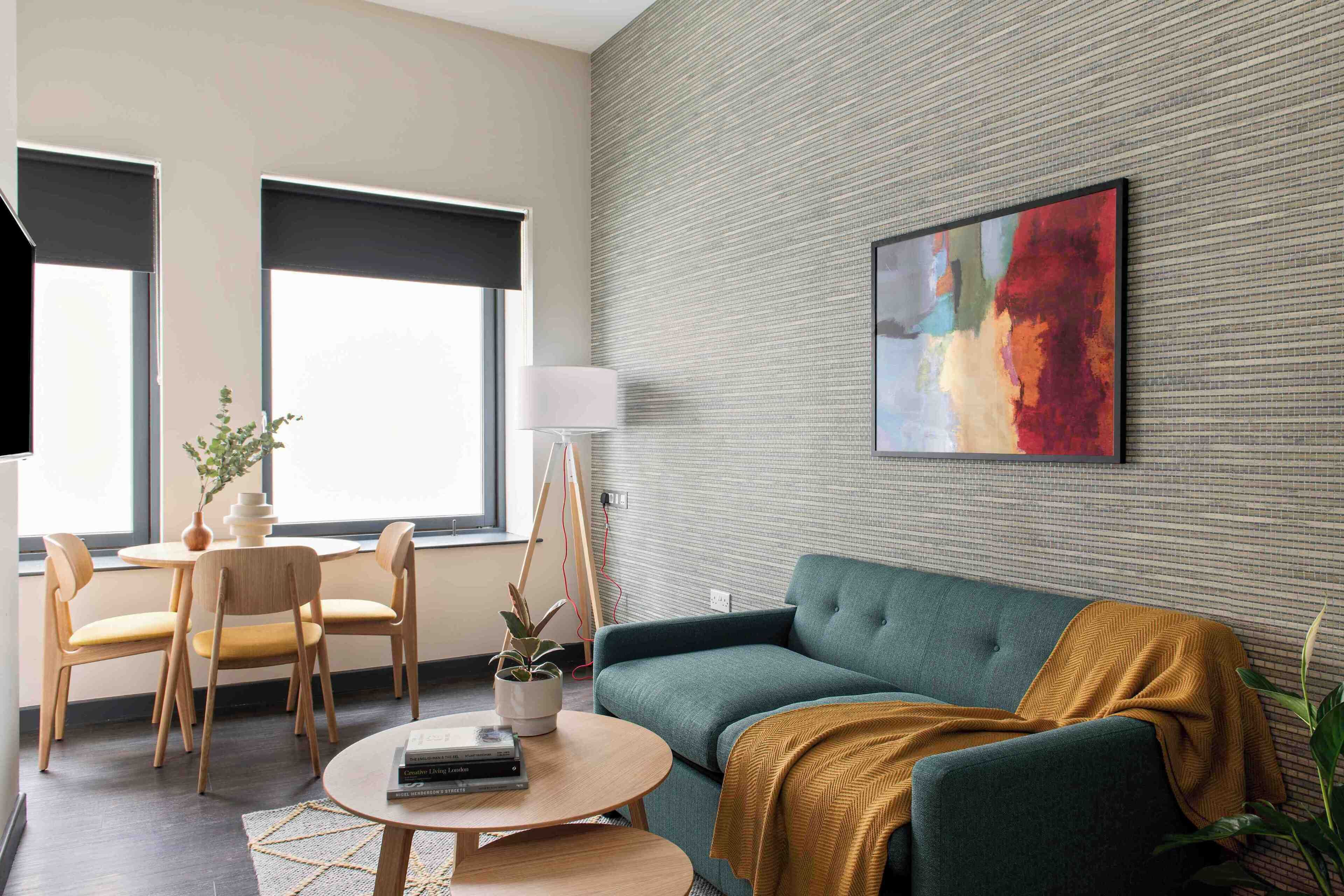 A modern living room with a green sofa, a round coffee table, a lamp, and a painting on the wall.