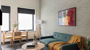 A modern living room with a green sofa, a round coffee table, a lamp, and a painting on the wall.