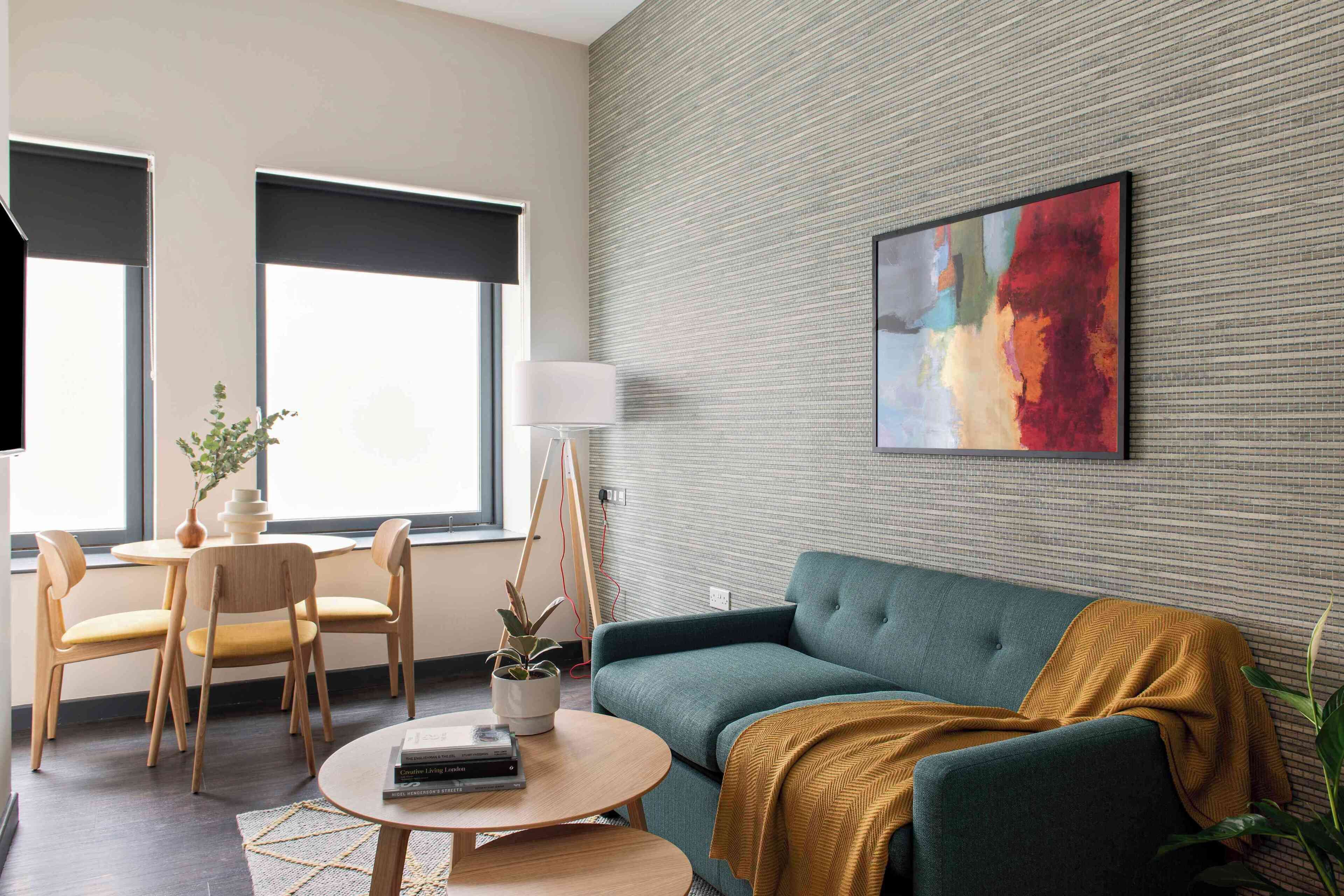 Una sala de estar moderna con un sofá, sillas, una mesa de centro y un cuadro en la pared.