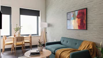 A modern living room with a sofa, chairs, a coffee table, and a painting on the wall.