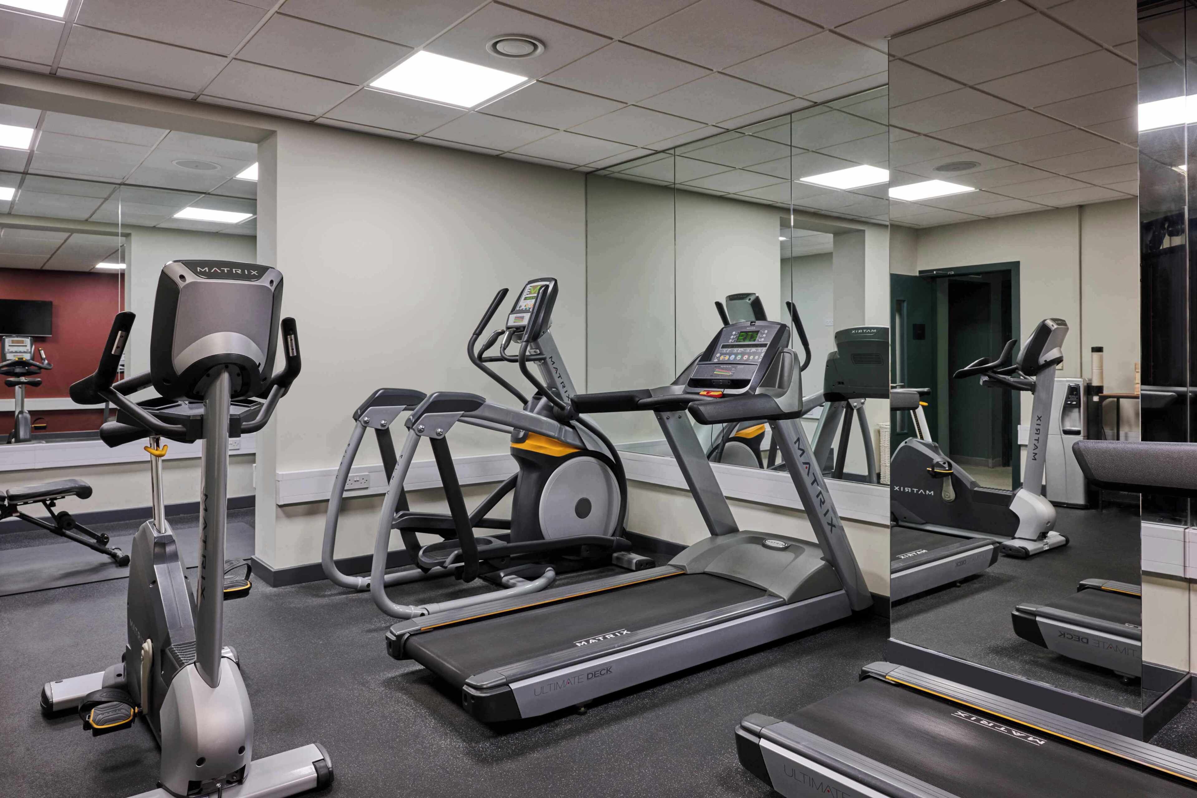 Une salle de sport équipée de tapis de course, d’appareils elliptiques et de vélos d’appartement.