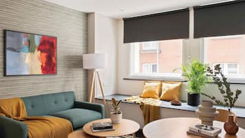 A modern living room with a sofa, a coffee table, a floor lamp, and a large window with blinds.