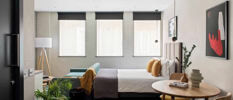 Een moderne hotelkamer met een bed, bureau, stoel en raam.