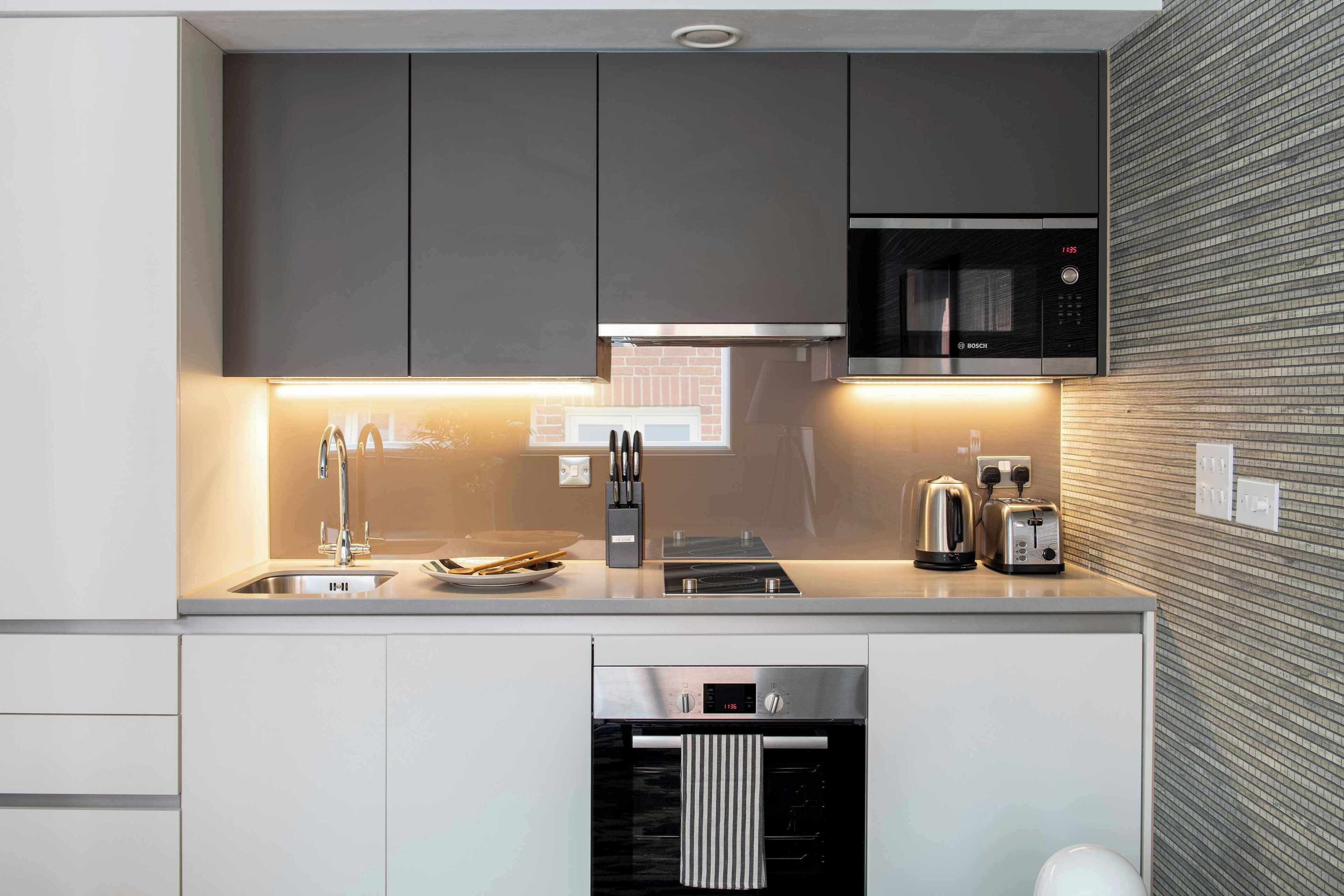 A modern kitchen with a built-in microwave, a kettle, and a toaster.