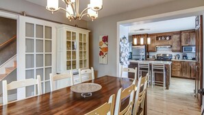 A spacious kitchen with wooden cabinets, a dining area with a round table, and a staircase leading to another level. - La Maison du matelot (Alma)