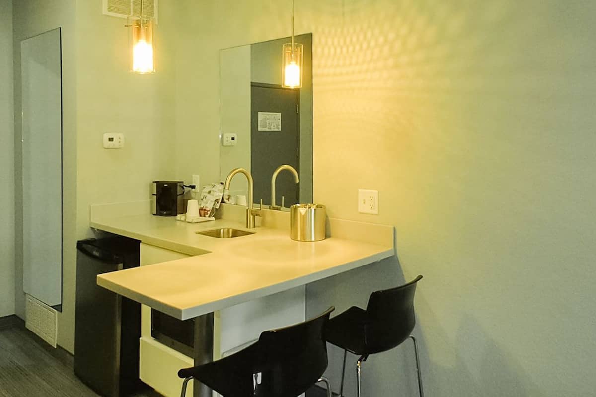 A modern kitchen with a sink, two chairs, a coffee maker, and a kettle.