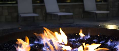 A fire pit with flames, surrounded by outdoor seating.